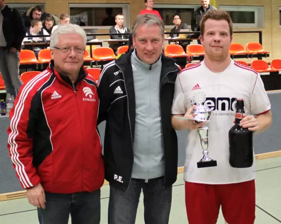 Patrick Laube (rechts) erhielt als<br>Kapitän von Uetersen II von Liga-<br>Trainer Peter Ehlers (Mitte) den<br>Sieger-Pokal; links im Bild<br>Betreuer Wolfgang Brandt.