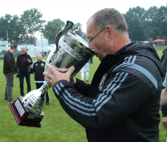 HMTV-Fußball-Abteilungsleiter Michael Kirmse nimmt einen Schluck aus dem Siegerpokal.