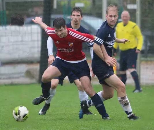 Der Appener Sebastian Hammer (im roten Trikot) ist hier vor den Hetlingern Philipp Drews (rechts) und Maximilian Heilborn (hinten) am Ball.